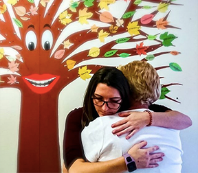 two people embracing next to smiling tree painting