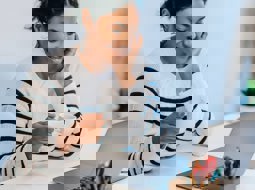 Smiling woman looking at computer with a cup of tea