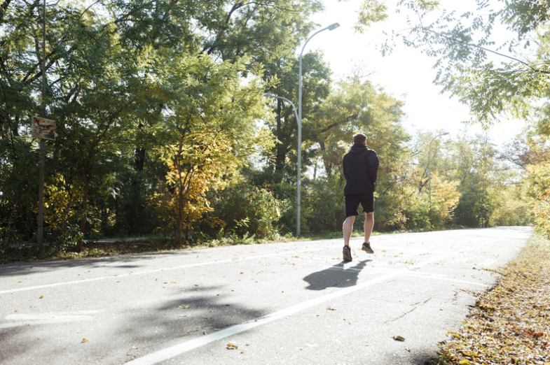 Man running on a pavement through a park