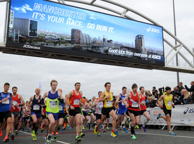 Runners on the course running under a bridge in Manchester
