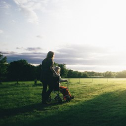 woman pushing person in wheelchair across a field