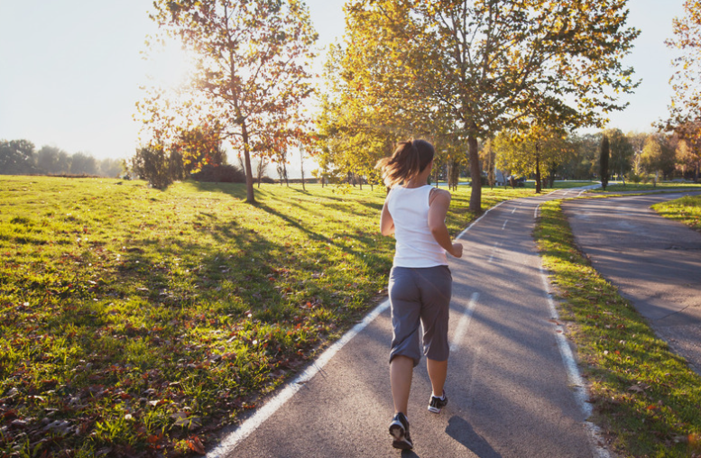 Woman running on pavement through a park